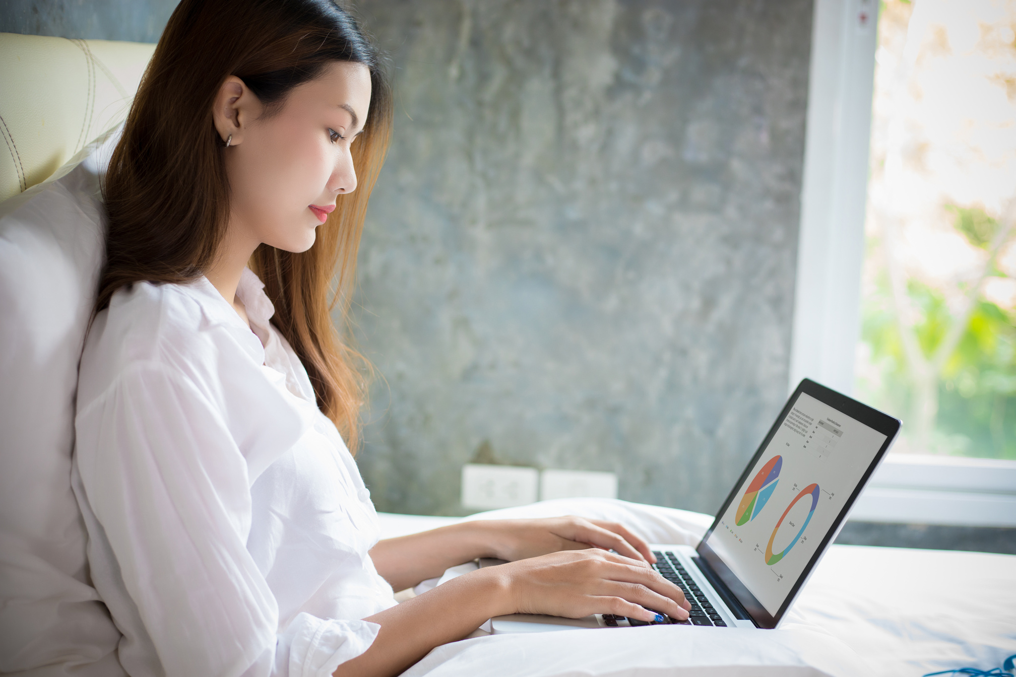 Woman Using Laptop while Sitting on Bed